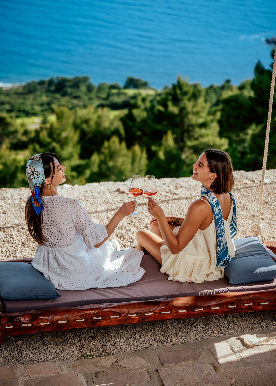 Two travellers toasting rosé wine at a viewpoint above the Adriatic