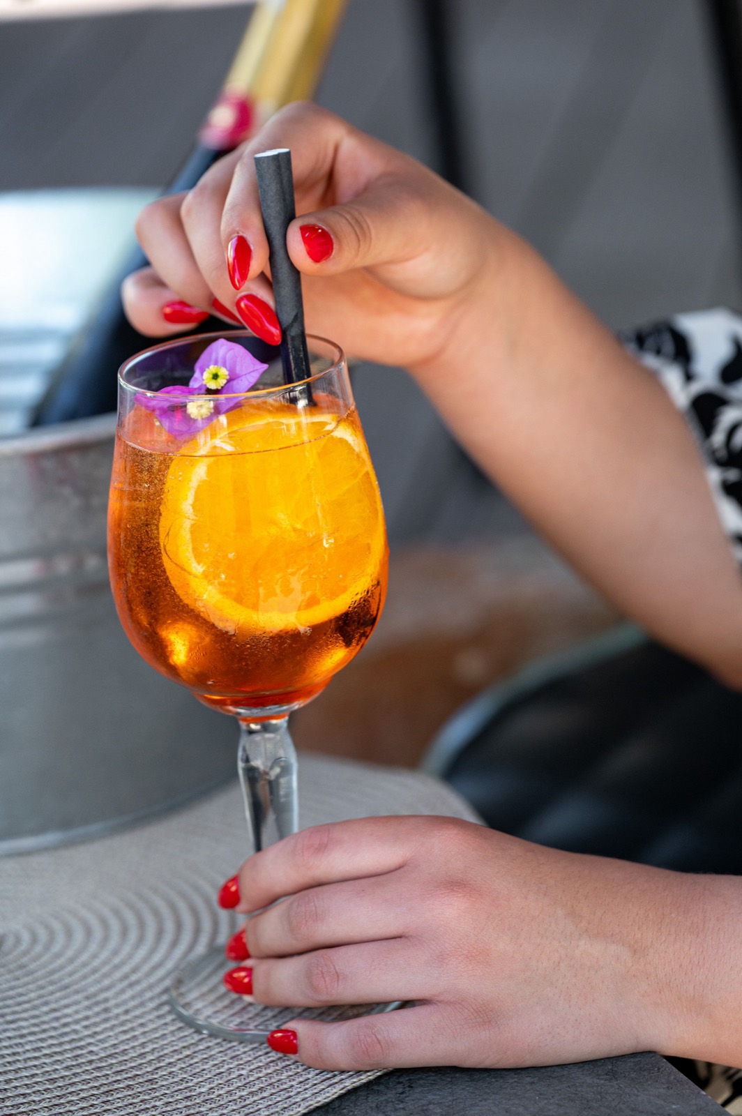 An Aperol spritz garnished with orange and an edible flower by the sea