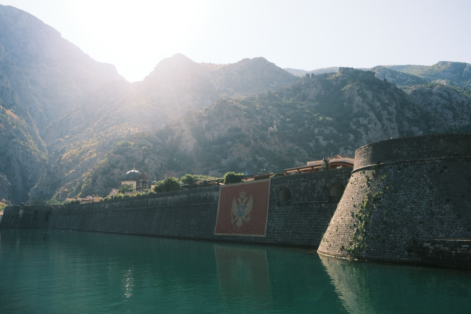 The old stone walls and bastion of Kotor rising from the water below the mountains