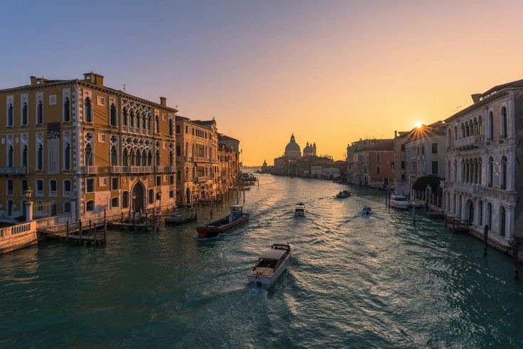 Boats on the Grand Canal in Venice at sunset with the basilica in the distance