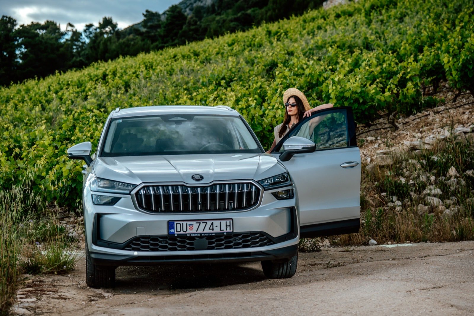 A traveller stopped beside a rental car on a track through Croatian vineyards