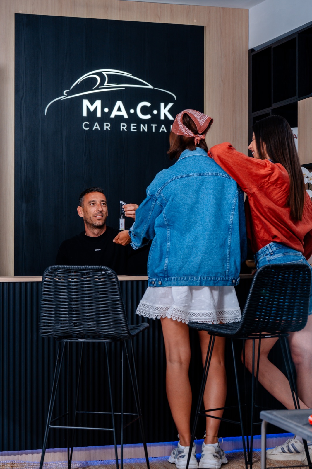 Two customers at the counter of the M.A.C.K. Car Rental office