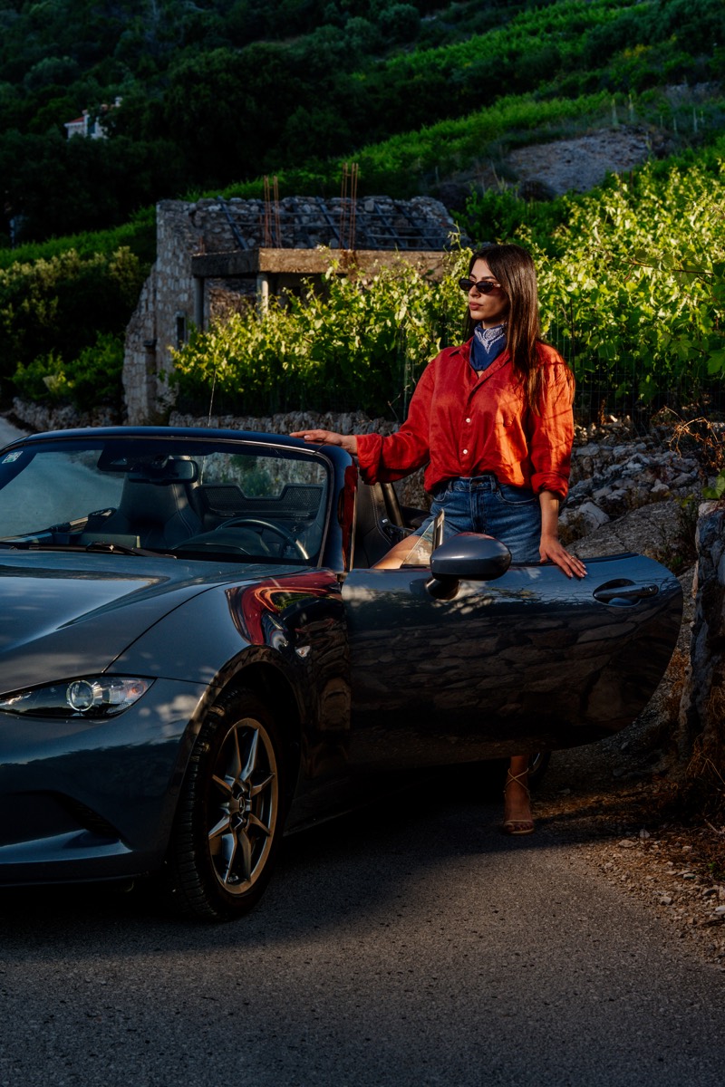 A guest seated on a Mazda MX-5 in front of the vineyards