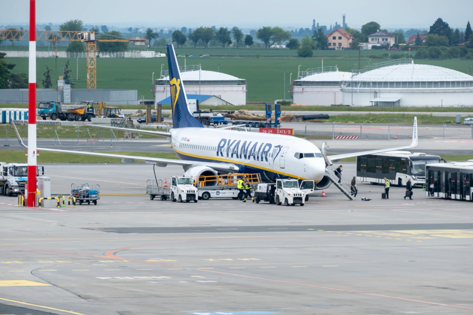 A Ryanair plane parked on the apron with passengers boarding from the tarmac