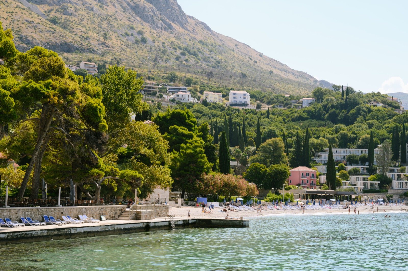 The bay at Župa Dubrovačka with a pebble beach, pine trees and villas on the hillside behind
