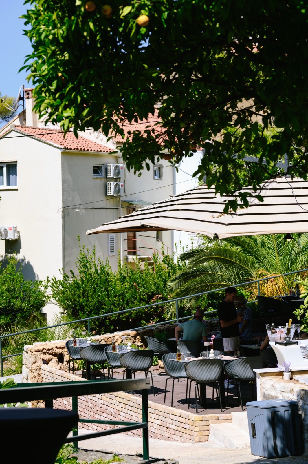 A restaurant terrace with parasols under orange trees in Srebreno