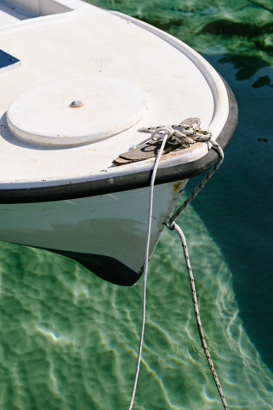 The bow of a small boat floating above bright turquoise water
