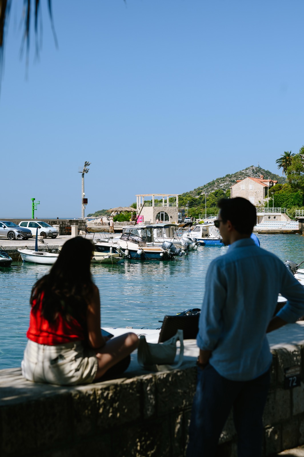 A couple looking out over the small harbour and moored boats at Mlini