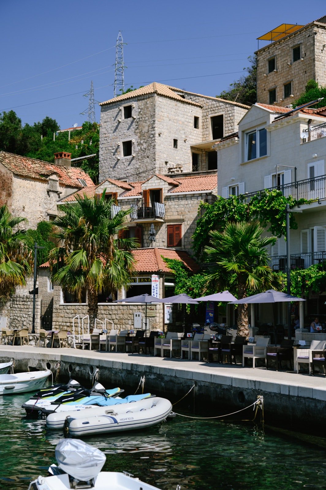 Restaurant terraces and moored boats along the harbour front in Mlini