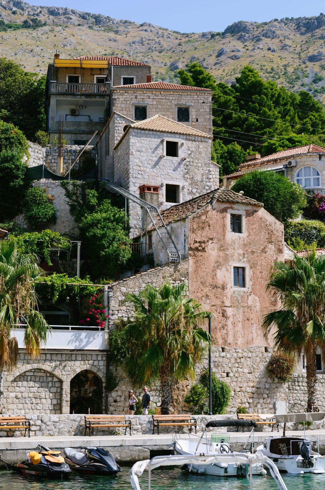 Stone houses and palm trees rising above the waterfront in Mlini